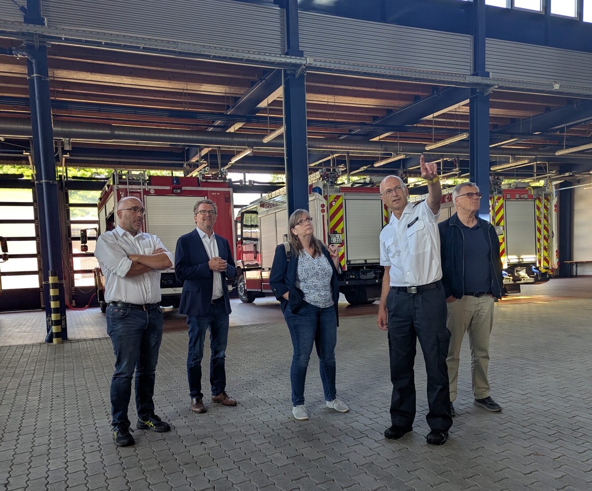 Fünf Personen stehen in einer gr0ßen Halle vor mehreren Feuerwehrfahrzeugen. v.l.n.r.: Thomas Weimar (Vizepräsident LfBK), Carl-Bernhard von Heusinger (MdL), Christine Reeka (Stadträtin), Réné Schubert (Präsident LfBK), Dr. Ulrich Kleemann (Stadtrat)
